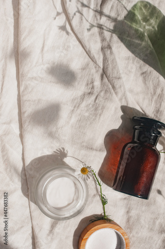 Sustainability concept cosmetic background brown glass green glass flowers camomille veil with product flat lay green natural beauty blog concept