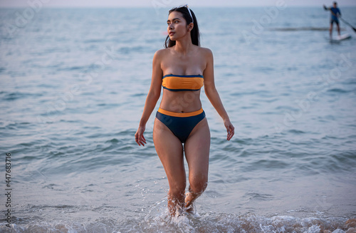 Outdoor summer portrait of the front image of beautiful girls in a sexy bikini walk up from the sea to the beach in summer