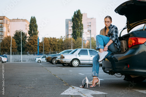 Driving Shoes For Car Enthusiasts. Driving Shoes for Woman To Wear on the Road. Woman changes high heels shoes in comfortable sneakers before driving, sitting in car