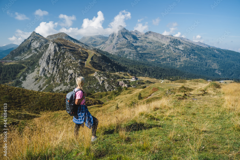 Woman with backpack enjoying view over Passo Rolle, - Italy , Dolomites. Scenery from summer vacation