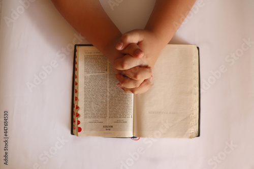 A Person is Folding Hands on the Bible in Indonesian Language to Pray photo