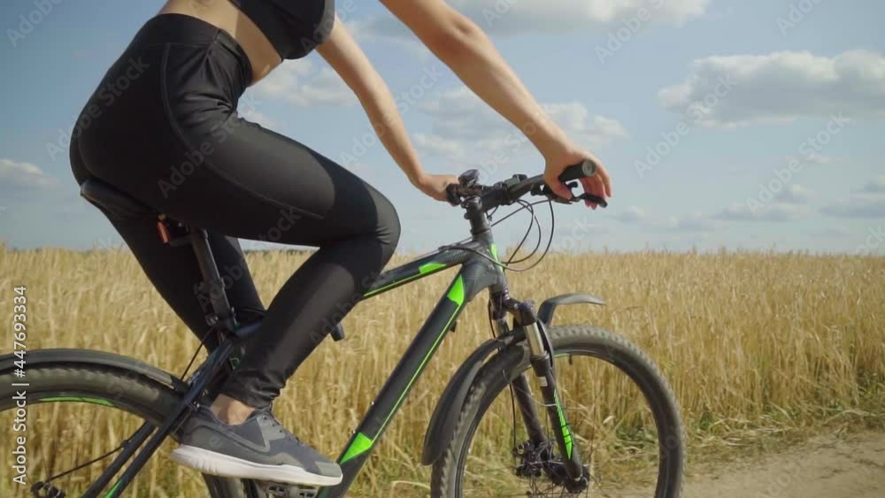 A woman rides a bicycle. A young woman rides a bicycle on a rural road in a field on a sunny day. She trains on a sports bike and sheds extra pounds to maintain a beautiful figure. slow motion, A woman rides a bicycle. A young woman rides a bicycle on a rural road in a field on a sunny day. She trains on a sports bike and sheds extra pounds to maintain a beautiful figure. slow motion,