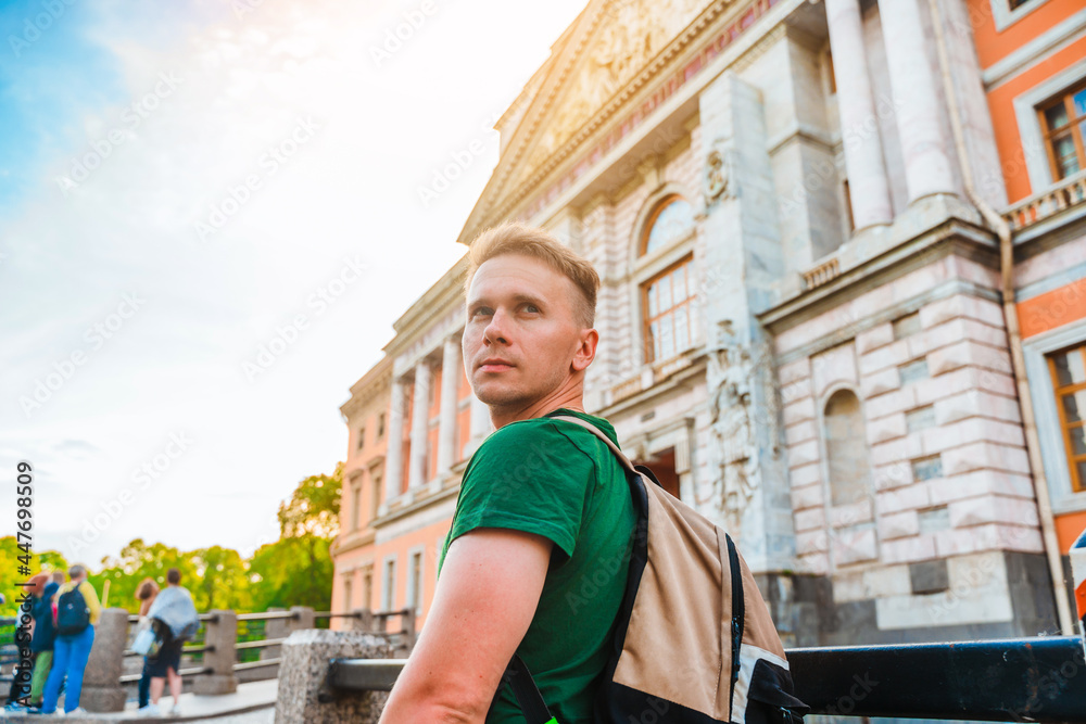 A young man in the center of St. Petersburg looks at the beautiful historical facade of the museum