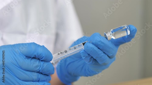 Doctor wearing blue gloves is using a syringe to suck up vaccines to prepare vaccines to prevent coronavirus covid-19.