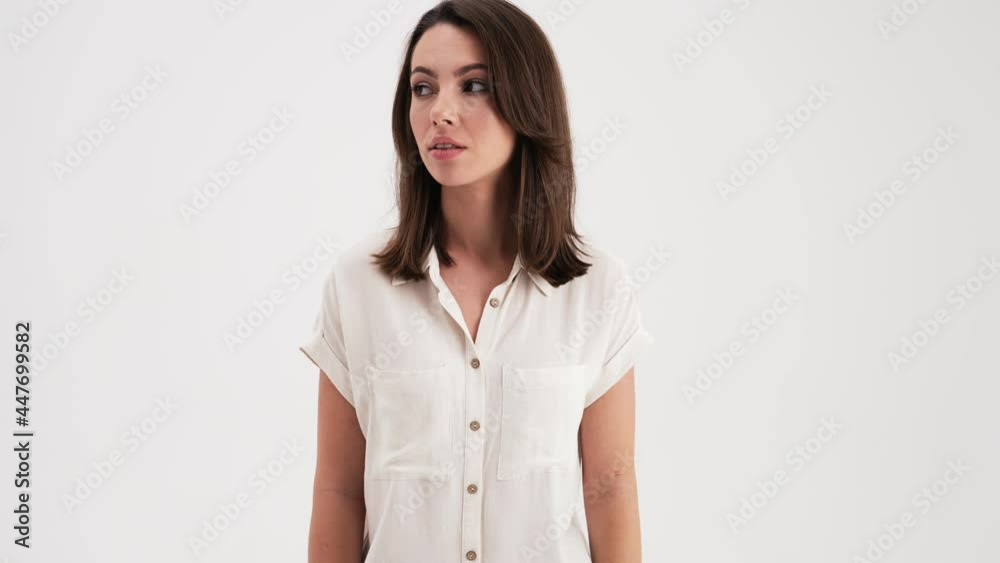 A beautiful woman wearing shirt is doing silence gesture standing in the studio isolated over white background A beautiful woman wearing shirt is doing silence gesture standing in the studio isolated over white background