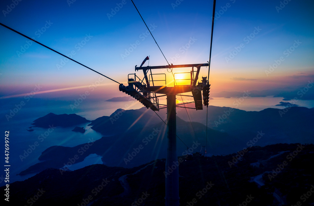 Babadag Skywalk funicular at sunset with sunlight beams on skyline. Panoramic view from the Fethie cable car on islands next to the coast of Oludeniz resort in Mugla province, Turkey.