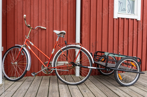 Bike with trailer parked in front of red wooden house on the island on Swedish west coast