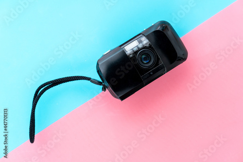 Compact film camera on a pink turquoise background