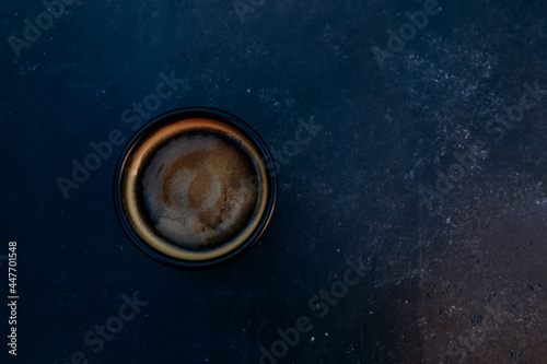 Dark mug of espresso or Americano top view. Black coffee cup on concrete table background. For coffee shop templates, cafe, morning, hot drink, caffeine concept