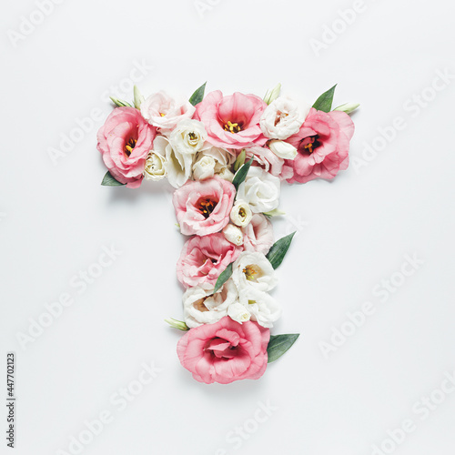 Letter T made with flower and leaves on bright white background. Floral mother's day alphabet concept. Spring blossom, valentine or romantic font collection. Flat lay, top view.