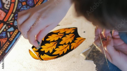 The artist is working on the creation of a stained glass window, top view. Drawing on the stained-glass details. Handmade.