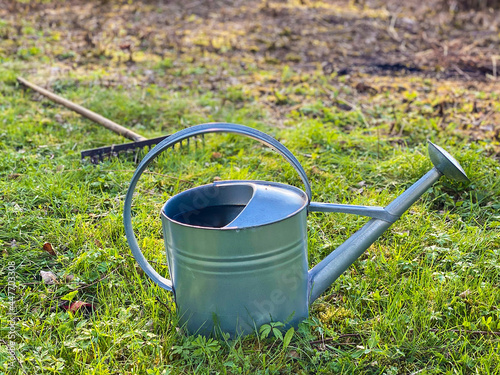 Metal watering can on grass.