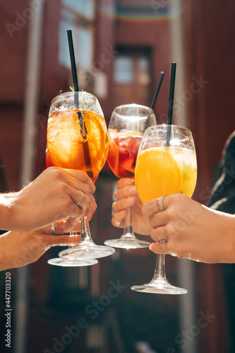 Friends toasting, saying cheers holding tropical cocktails. Making celebratory toast 