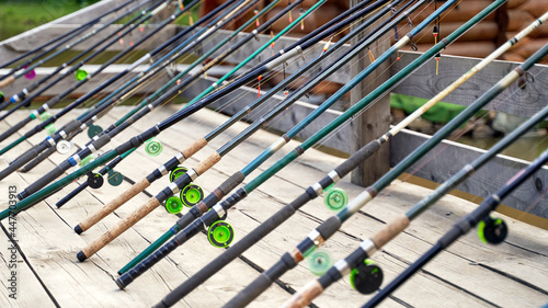 Obraz na płótnie Many fishing rods on the wooden pier by the river or lake on a sunny day w salonie