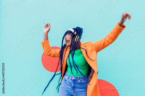 Italy, Milan, Stylish woman with headphones dancing against wall