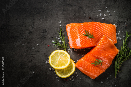 Fotografie, Obraz Salmon fillet at cutting board with ingredients for cooking at black