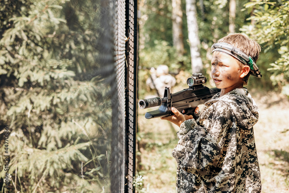 Boy with a weapon in his hand playing laser tag shooting game in outdoor. War simulation game Boy with a weapon in his hand playing laser tag shooting game in outdoor. War simulation game