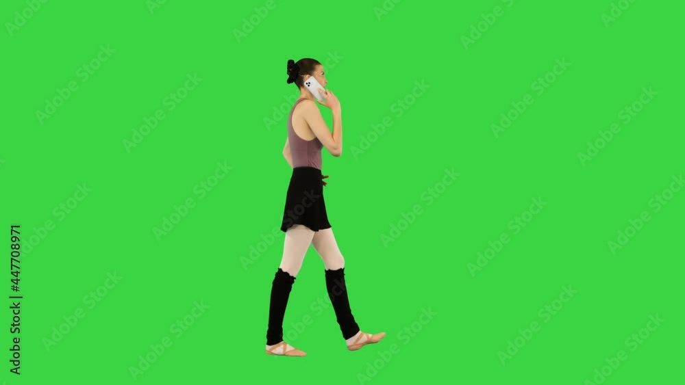 Young ballerina in training clothes walks talking on mobile phone, hand on hip on a Green Screen, Chroma Key. Young ballerina in training clothes walks talking on mobile phone, hand on hip on a Green Screen, Chroma Key.