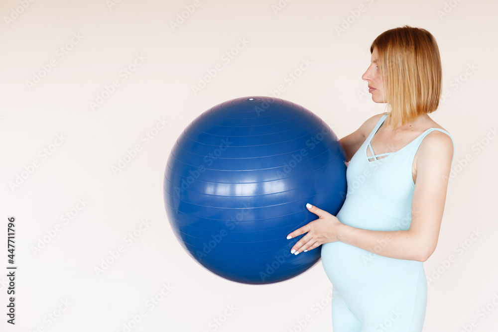 a pregnant woman with a sports ball in her sleeve on a light background. yoga for pregnant women