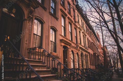 Row of old brownstone buildings along an empty sidewalk block in the Greenwich Village neighborhood of Manhattan, New York City NYC