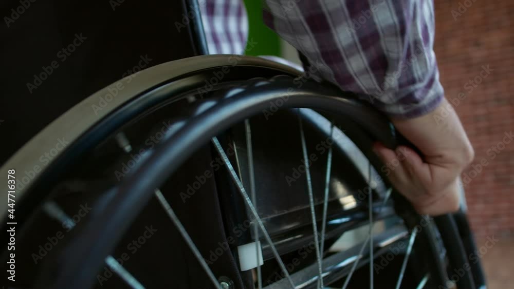Closeup hand disabled man in wheelchair turns wheel and goes forward, closeup. Man with special needs goes forward in wheelchair