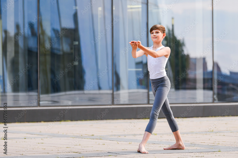 ballet boy teenager dancing against the background of reflection of the city and sky in the glass wall ballet boy teenager dancing against the background of reflection of the city and sky in the glass wall