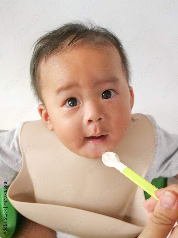 A happy asian baby boy sitting and feeding some pap pudding by mom with spoon. A happy asian baby boy sitting and feeding some pap pudding by mom with spoon.