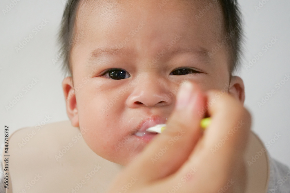 A happy asian baby boy sitting and feeding some pap pudding by mom with spoon. A happy asian baby boy sitting and feeding some pap pudding by mom with spoon.