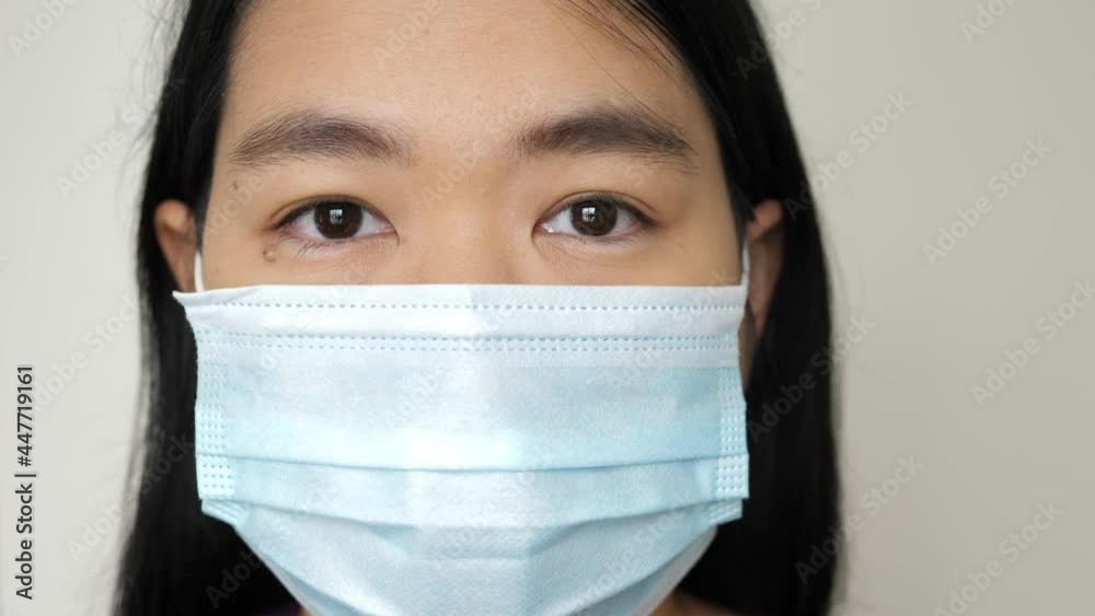 Closeup face asian woman wearing surgical mask protect from coronavirus, covid 19, looking to camera. Concept of health care. Closeup face asian woman wearing surgical mask protect from coronavirus, covid 19, looking to camera. Concept of health care.