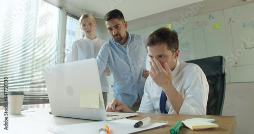 Stressed shocked diverse workers office team frustrated about business failure reading bad news results or email looking at laptop, depressed upset colleagues having problem