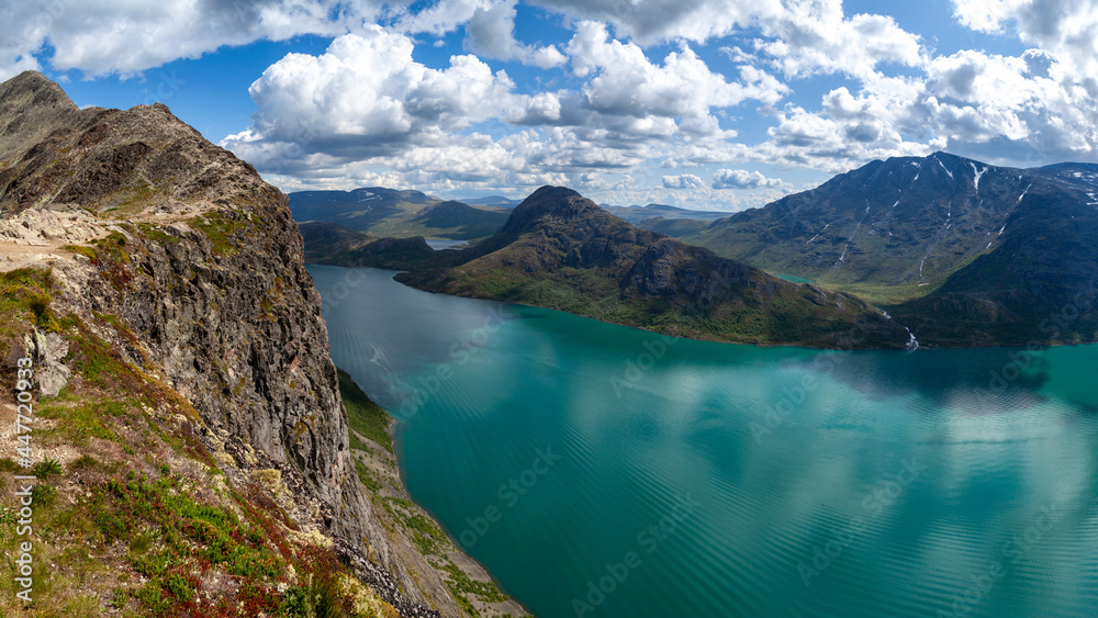 Besseggen weg inNational Park, Norway. View from the cliff of the picturesque panorama of the mountains on the horizon and on waters of Gjende Lake under blue skies. 