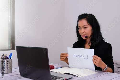 Asian young businesswoman student-teacher tutor wear wireless headset video conference calling on laptop computer talk by webcam learn to teach in online chat, distance webinar online teaching concep