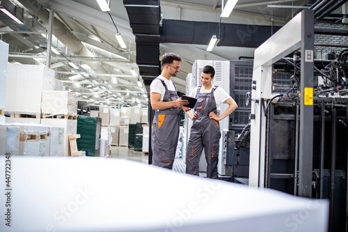 Print workers discussing about product design and color matching in modern print house. photo