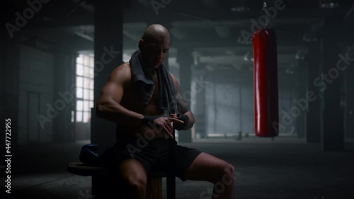 Boxer wrapping hands in boxing tapes. Focused sportsman using punching wraps 