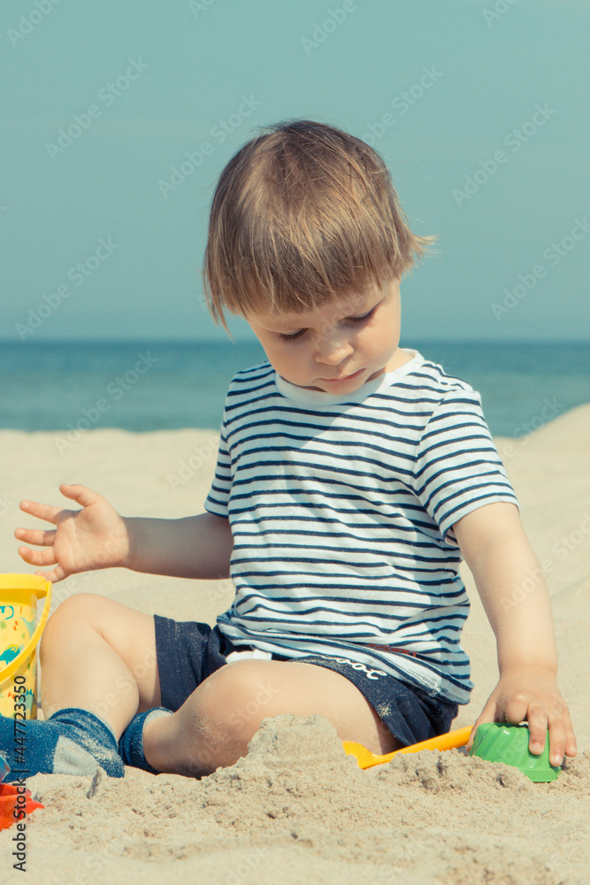 Smiling boy playing on sand at beach. Summer, vacation and relaxation time concept Smiling boy playing on sand at beach. Summer, vacation and relaxation time concept