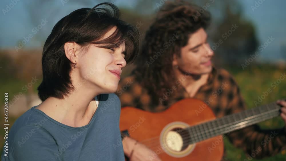 sing at park - young woman sings accompanied by her friend playing the guitar sing at park - young woman sings accompanied by her friend playing the guitar