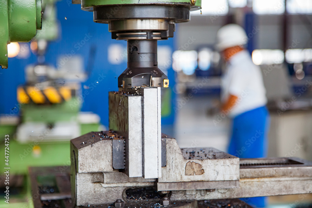 Close up of milling machine tool and steel part in vise. Metal shavings. Worker on background blurred. Atyrau, Kazkahstan. Close up of milling machine tool and steel part in vise. Metal shavings. Worker on background blurred. Atyrau, Kazkahstan.
