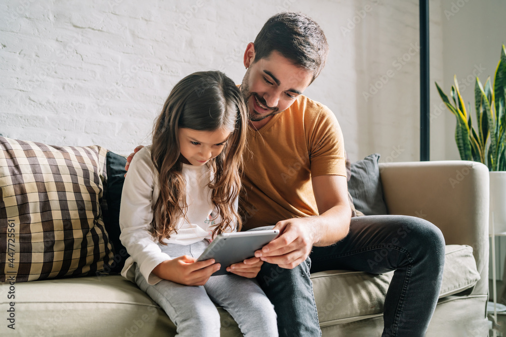 Little girl and her father using a digital tablet at home. Little girl and her father using a digital tablet at home.