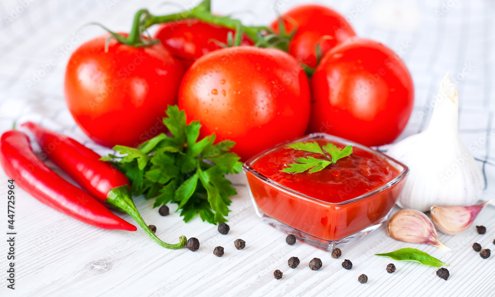 Ripe tomatoes and homemade ketchup on the table. The concept of cooking sauce or ketchup. Close-up. Ripe tomatoes and homemade ketchup on the table. The concept of cooking sauce or ketchup. Close-up.