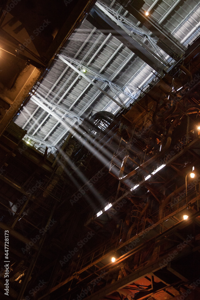 Interior of electric power plant with giant boiler (right). Sun rays in steamed air. Profile roof. Aksu, Kazakhstan.