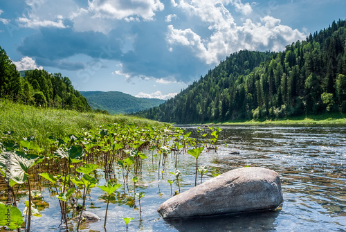 Landscape of Siberia. Kiya River, mountain banks and green forests in the Kemerovo region. Daytime landscape with blue skies and clouds. photo