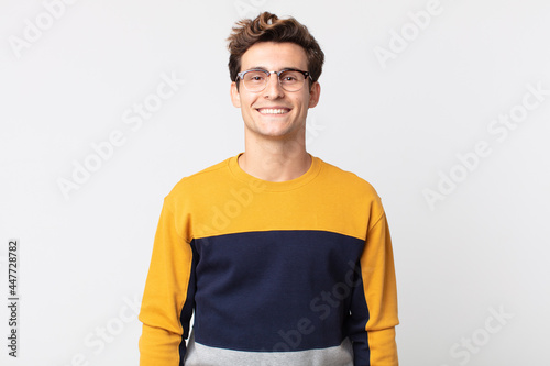 Obraz na plátne young handsome man looking happy and goofy with a broad, fun, loony smile and ey