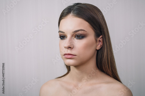 Beautiful teenage girl model getting professional make-up. Beauty portrait of female teenager in process of visage. Cosmetics, beauty standards, skin care concept. Close up shot.