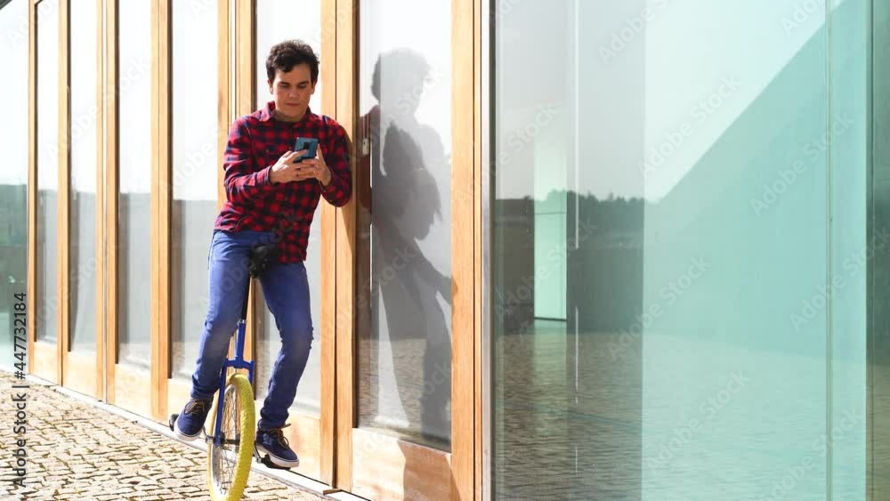Young man browsing mobile phone on unicycle on street Young man browsing mobile phone on unicycle on street