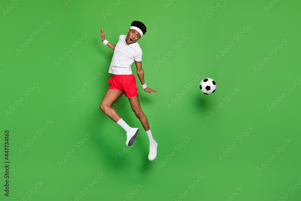 Photo of team player guy jump carefree kick soccer ball wear white t-shirt shorts sneakers isolated green color background Photo of team player guy jump carefree kick soccer ball wear white t-shirt shorts sneakers isolated green color background