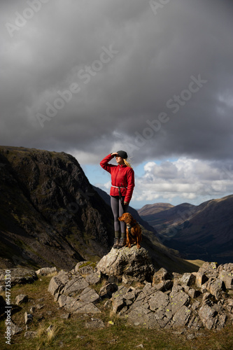 Travel lifestyle view of girl and adventure dog hiking by Great Gable near Scafell Pike mountain peak in Lake District National Park, England, UK. photo