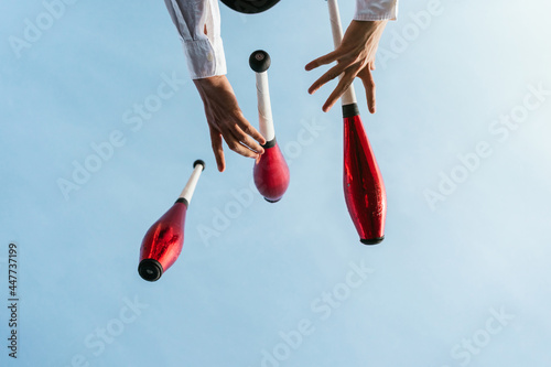 Juggler performing circus trick against blue sky