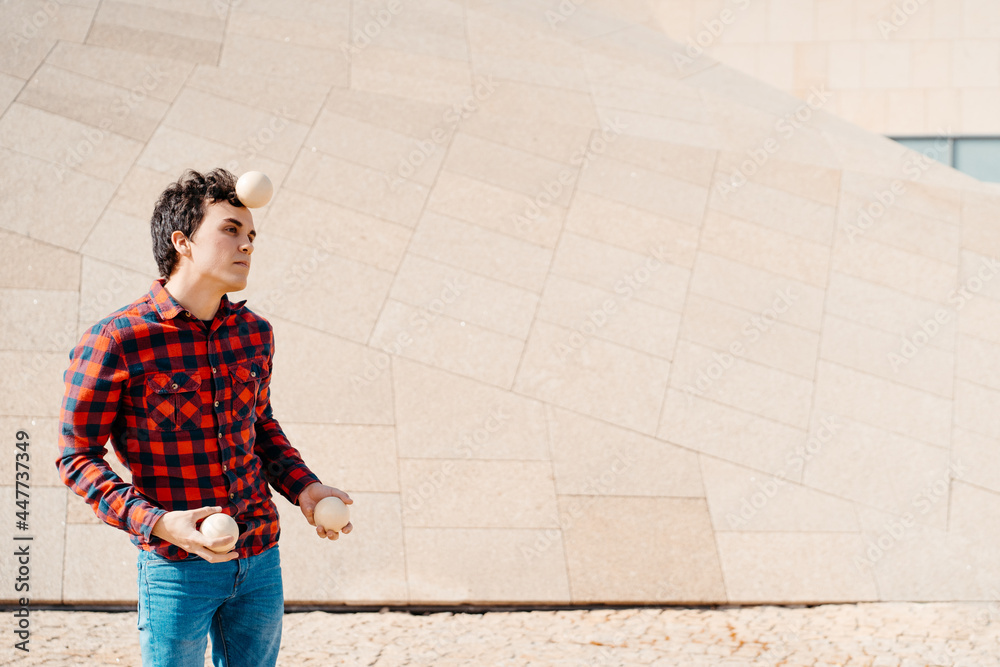 Young man juggling balls near modern building Young man juggling balls near modern building