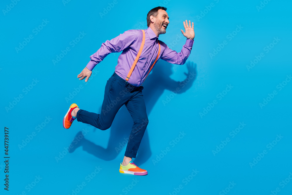 Obraz premium Full size profile side photo of excited mature man happy positive smile go walk run hurry isolated over blue color background