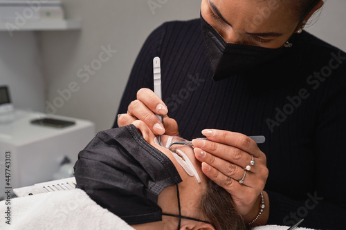 Cosmetologist doing eyelash extension procedure in beauty center photo